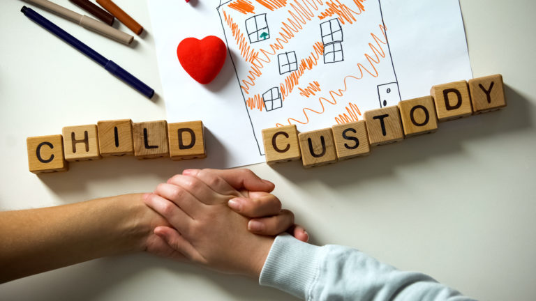 Child Custody in letter blocks with two hands holding