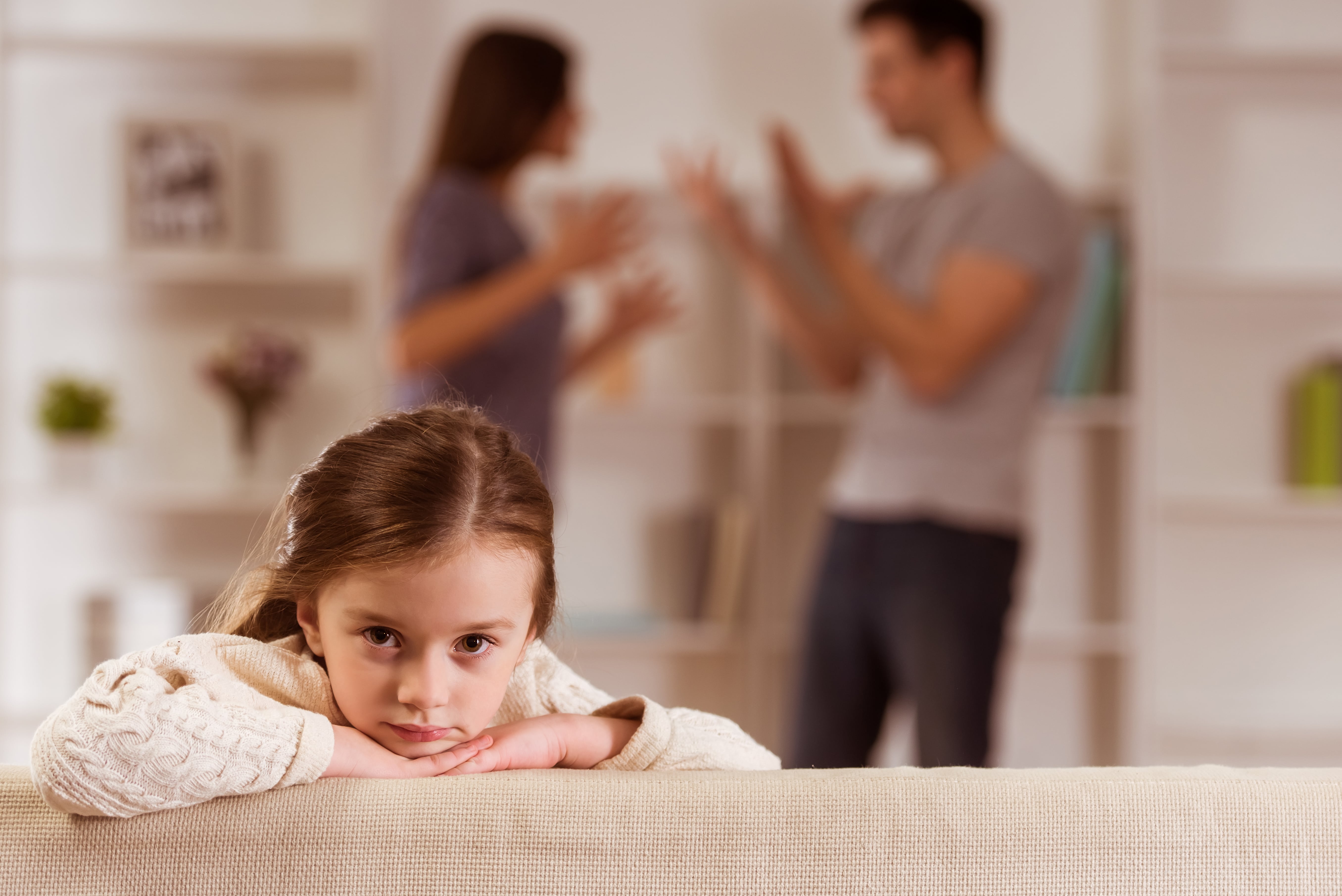 girl with parents arguing behind her